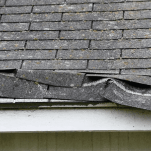 a roof with damaged, lifted up shingles