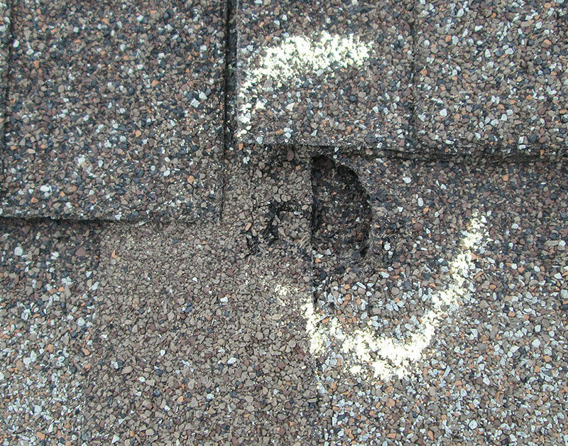 Visible dent in shingle roof from hail damage