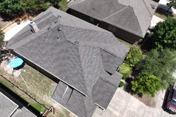 Aerial view of a residential house featuring dark gray, energy-efficient asphalt shingles.